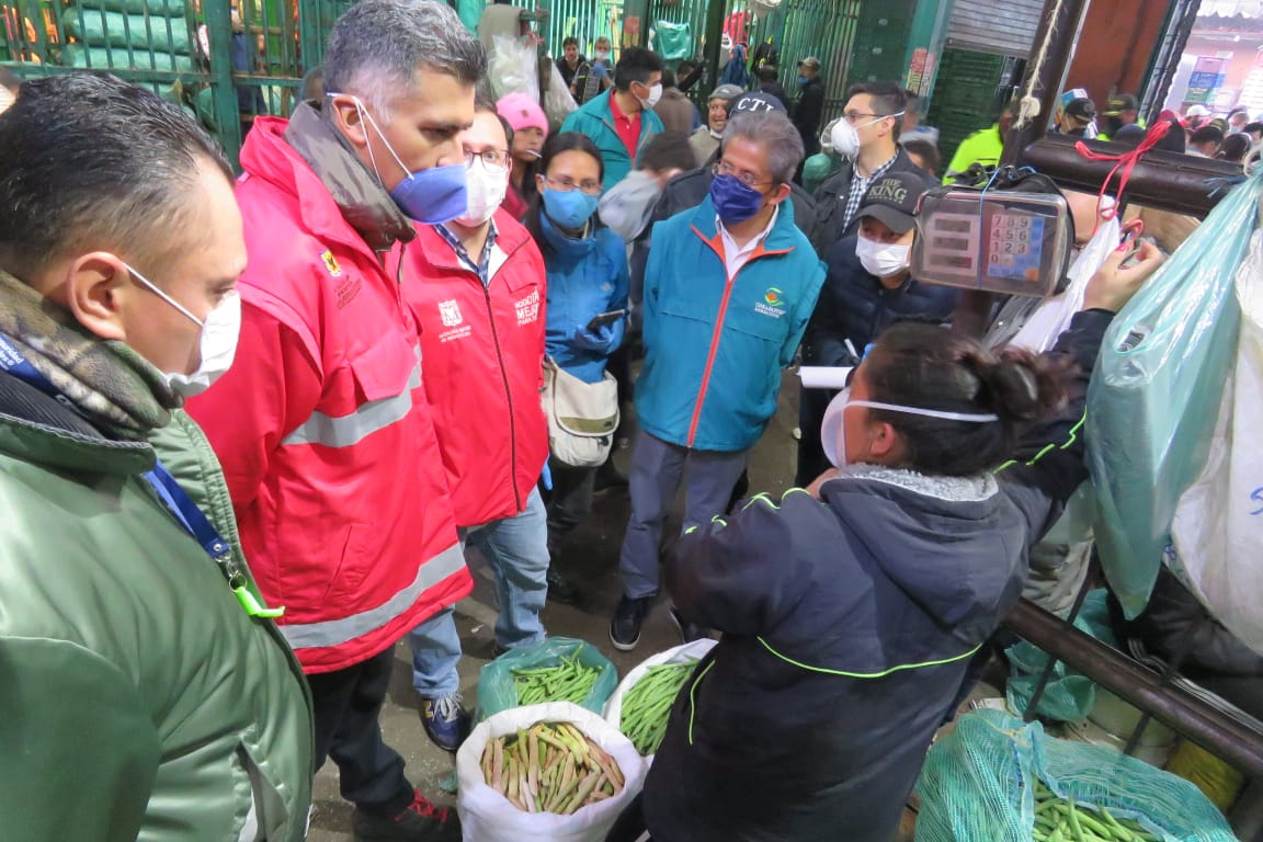 Dos funcionarios de la Alcaldía de Bogotá en compañía de varios comerciantes de Corabastos, realizando una jornada de verificación de precios y el abastecimiento de alimentos.