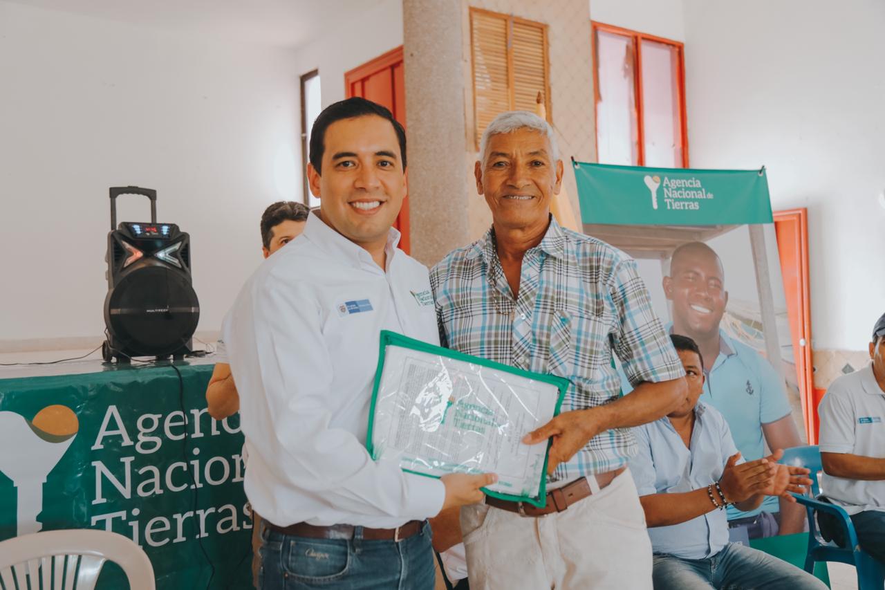 Aparecen dos personas, Campo Elías Vega, Subdirector de Tierras de la Nación, haciendo entrega del título de propiedad a Hernando Benítez, beneficiario de San Benito Abad, Sucre.