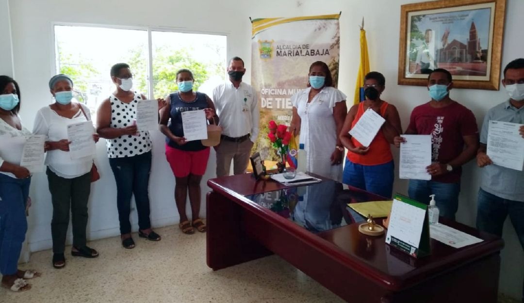 Grupo de personas mostrando los titulos de propiedad que se les entregaron
