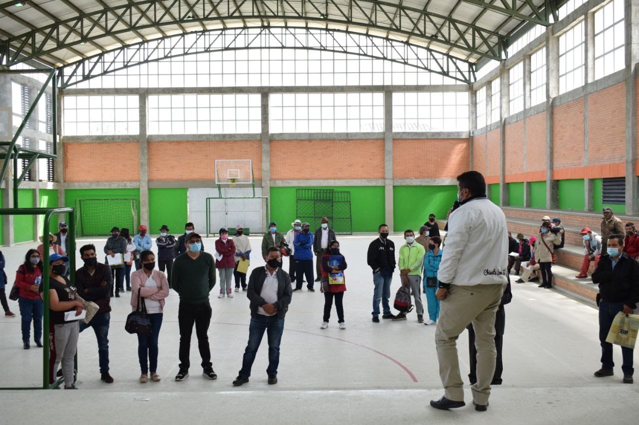 En cancha deportiva cubierta se reúnen varios campesinos y un funcionario de la ANT, quien por medio de un micrófono expone la jornada de registro de sujetos de ordenamiento territorial. 