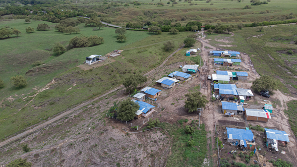 Fotografía tomada desde el cielo del pueblo de Patía Cauca. En ella se observan varias casas con techo color azul y a su alrededor terreno con pasto verde, árboles y partes de caminos destapados.