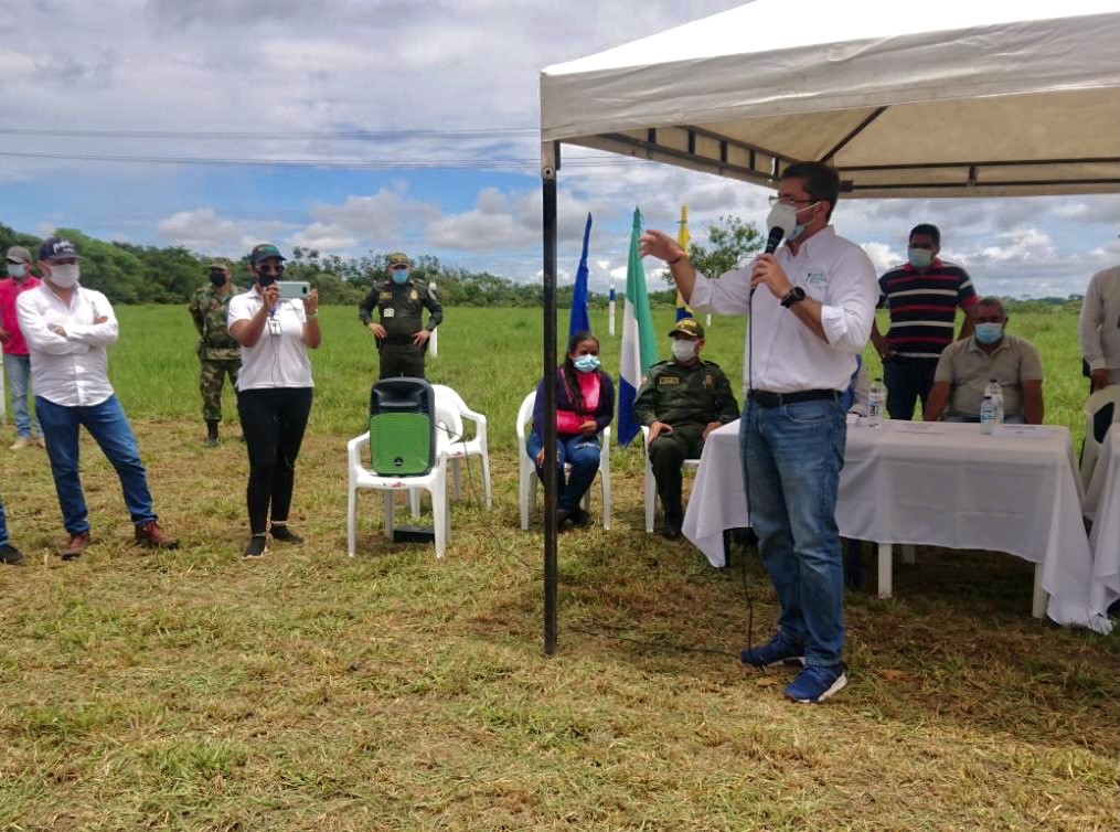 Funcionario de la ANT, vestido de camisa blanca, pantalón azul y tapabocas, en compañía de dos hombres policías, uno del ejercito y algunos campesinos, ubicados en una carpa instalada con una mesa cubierta por un mantel blanco, hacen oficial la entrega del predio La Esperanza en San José del Guaviare.