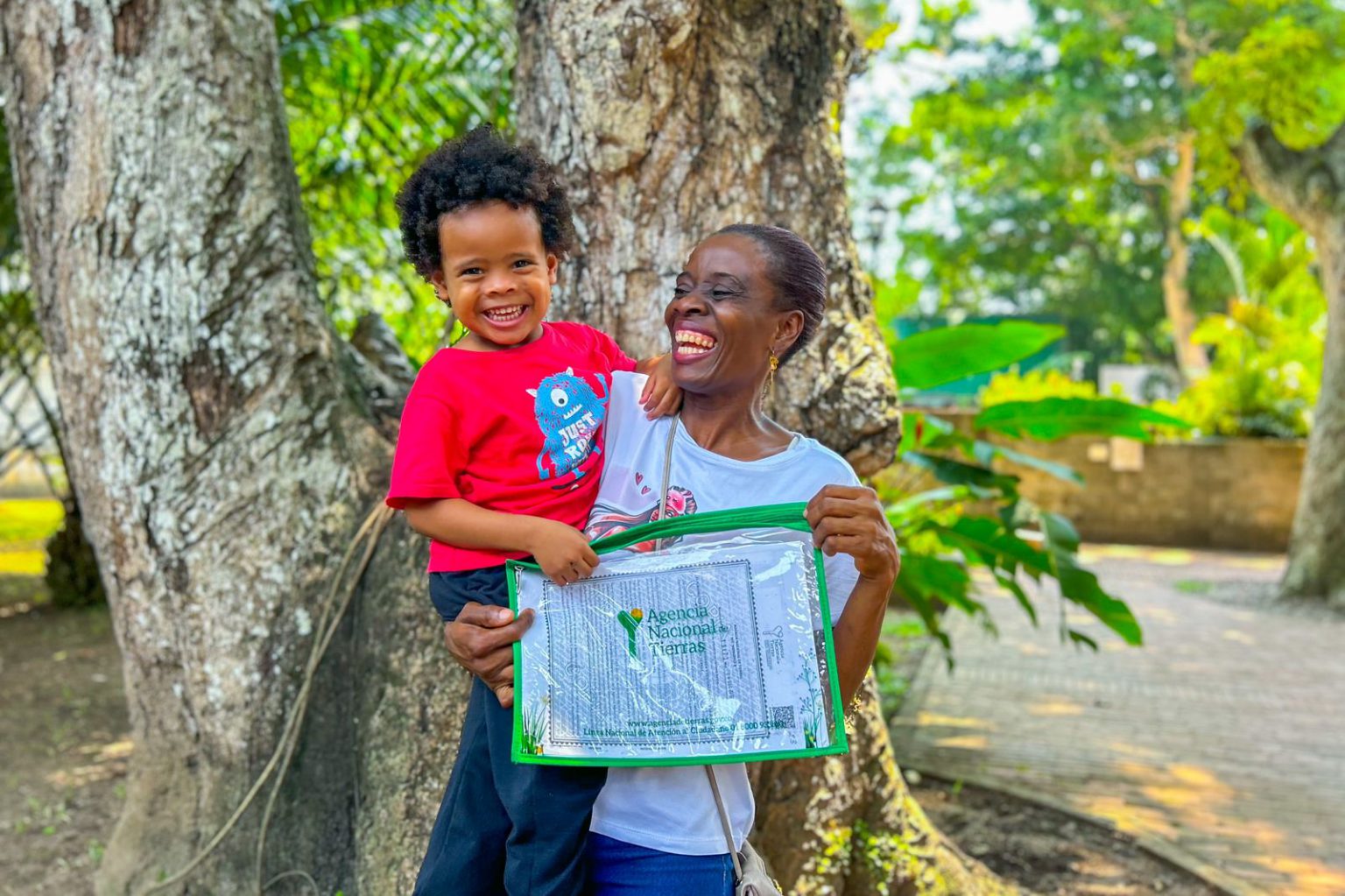 Mujer afro sonriendo con su titulo y su hijo en brazos.