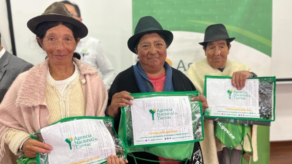 Tres mujeres campesinas recibiendo sus títulos.