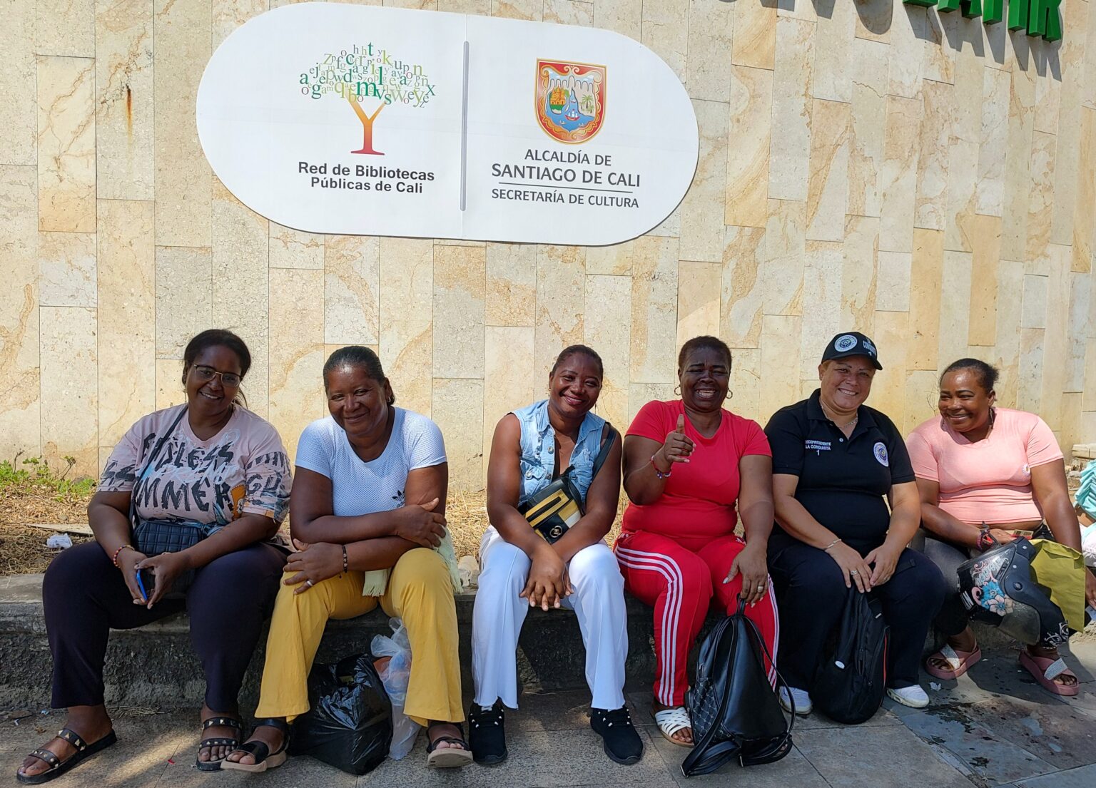 6 mujeres sentadas frente a la red de bibliotecas públicas en Cali.