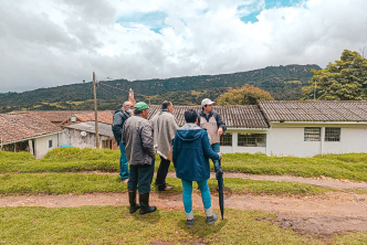 un-grupo-de-personas-parados-en-una-colina-mirando-una-casa